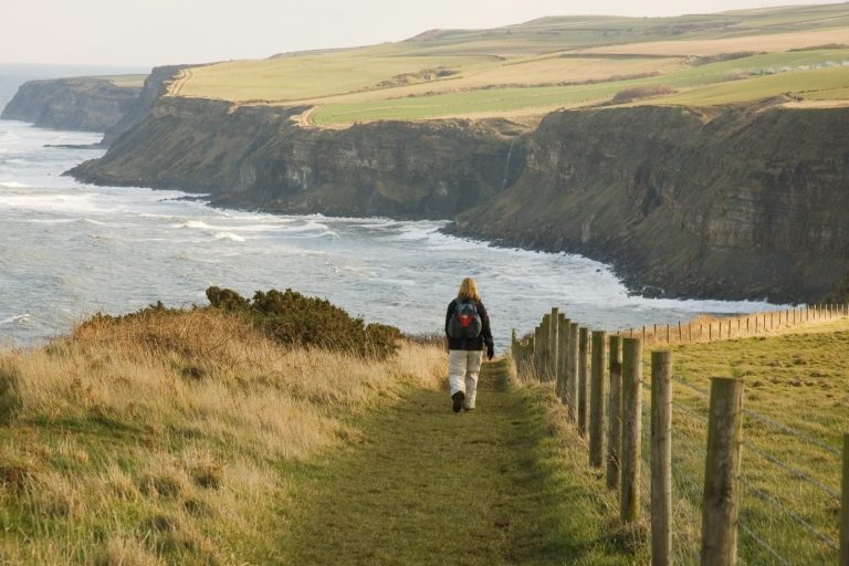 Woman walking the Cleveland Coast path along the coast line